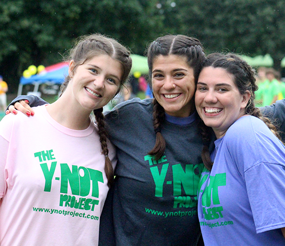 three smiling women at a Y-noT wiffle ball tournament.