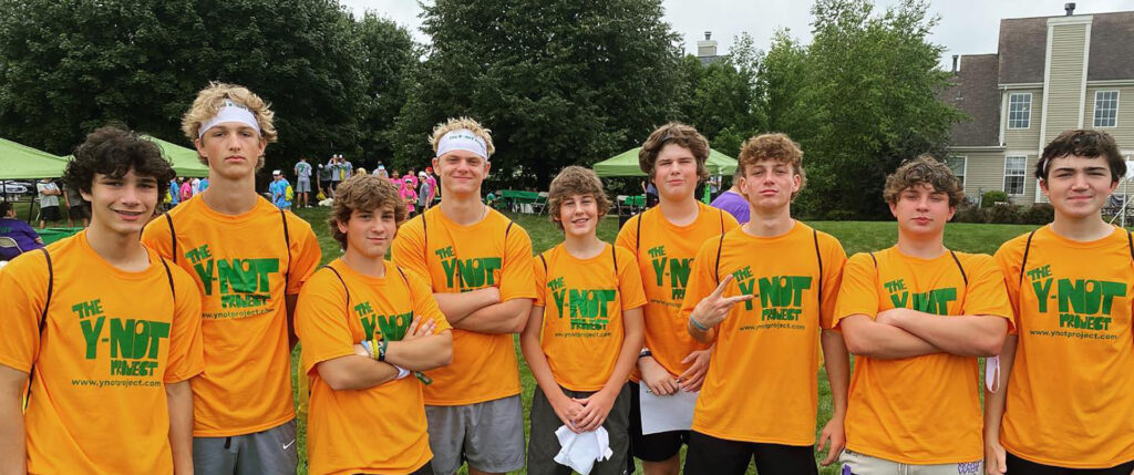 Group of teen boys in Y-noT orange and green t-shirts after participating in a wiffle ball event.