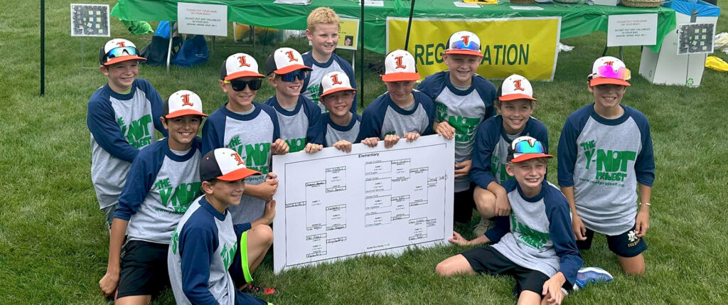 Elementary school team holding a chart with their winning stats in the Y-noT Wiffle Ball Tournament.